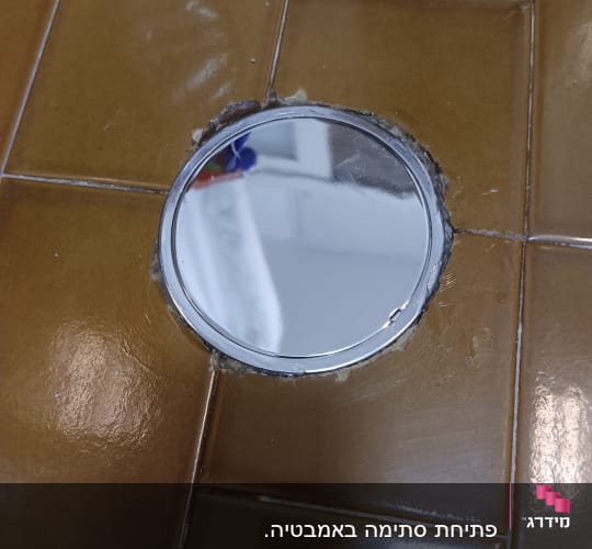 פתח ניקוז עגול ברצפת אריחים חומים